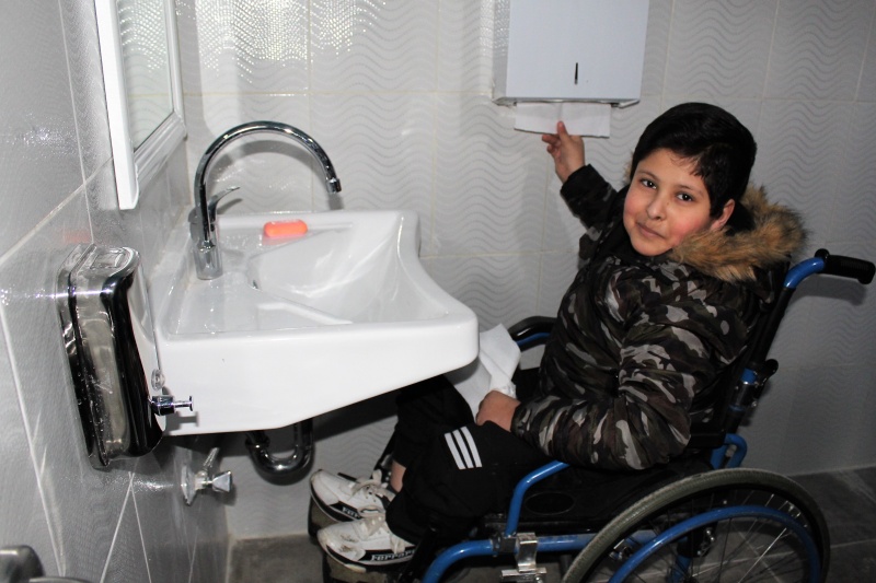 Junge im Rollstuhl an einem barrierefreien Handwaschbecken